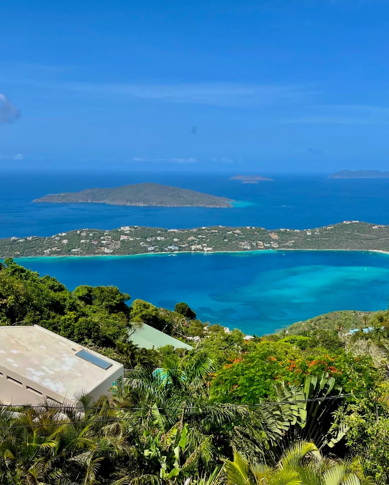 Hilltop view over a turquoise bay and small islands under a bright blue sky
